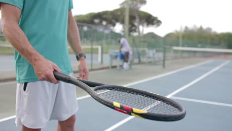 Portrait-of-caucasian-male-tennis-player-bouncing-ball-on-racket-at-outdoor-court-in-slow-motion