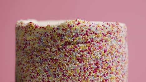 close up studio shot of revolving birthday cake covered with hundreds and thousands decorations 9