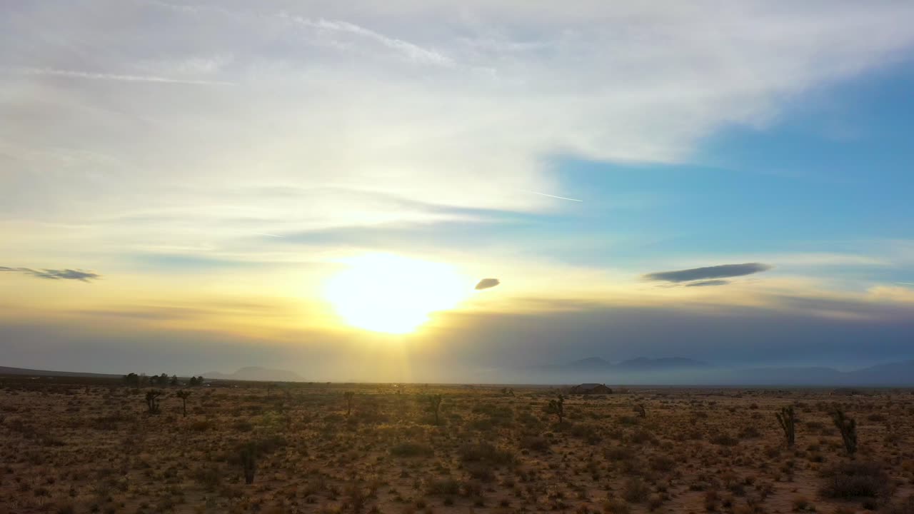 Slow sliding cinematic aerial view of a sunset over the Mojave Desert landscape and Joshua trees