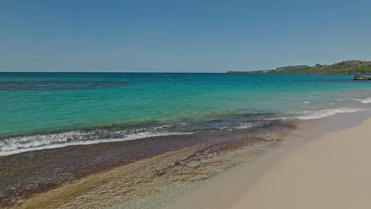 avión no tripulado volando a baja altitud sobre aguas claras y playa blanca de playa rincon