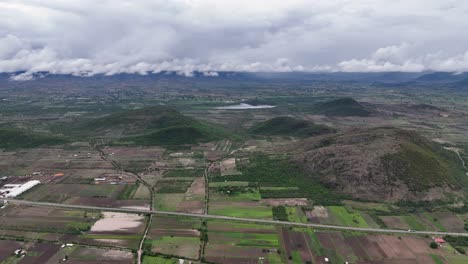 aerial view of lush green farmlands and hills under a cloudy sky