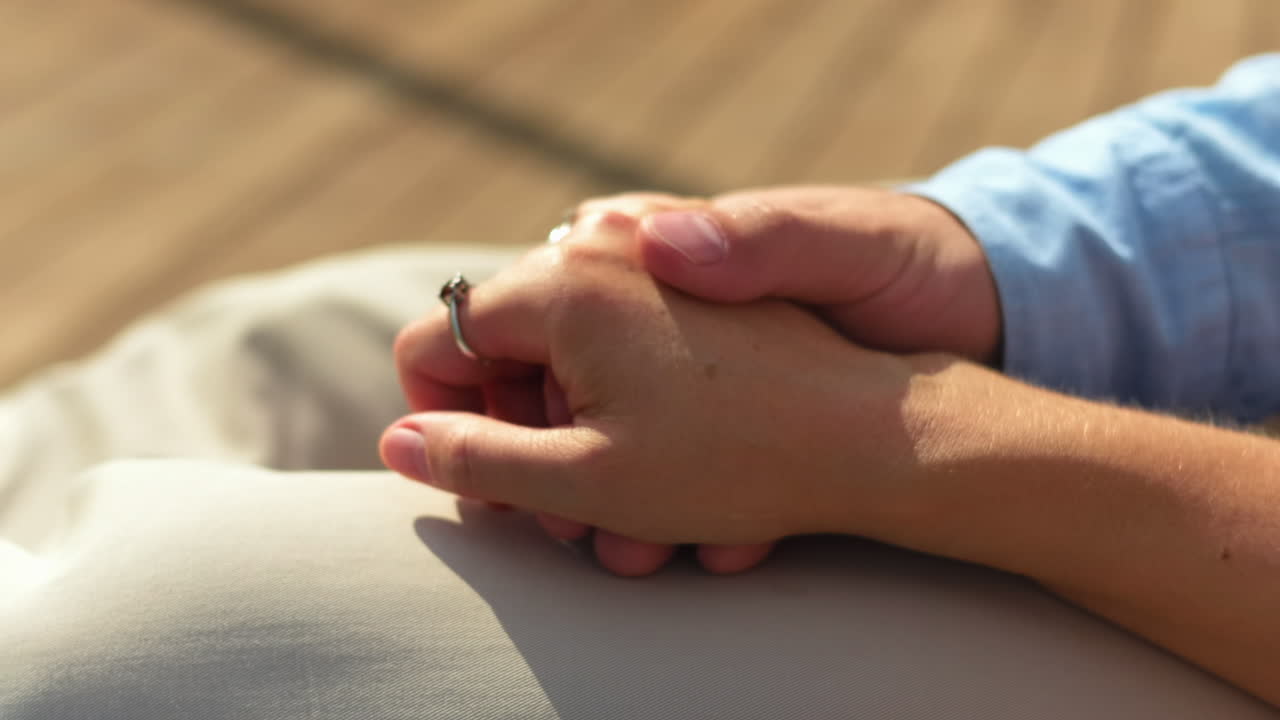 Primer plano de una pareja cogida de la mano con un anillo