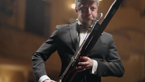 man with bassoon is playing music in scene of classical music hall musician in black suit