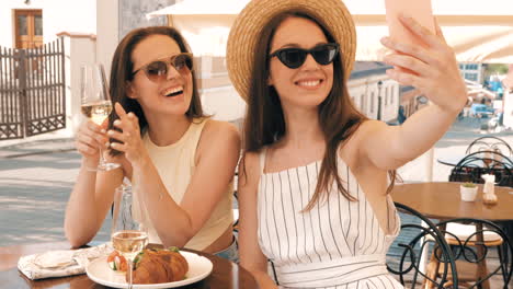 two happy friends taking a selfie at an outdoor cafe