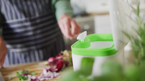 midsection senior caucasian woman standing in kitchen and cleaning waste