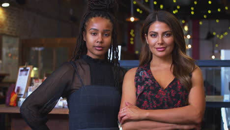 Portrait-Of-Two-Female-Coffee-Shop-Owners-Standing-At-Sales-Desk