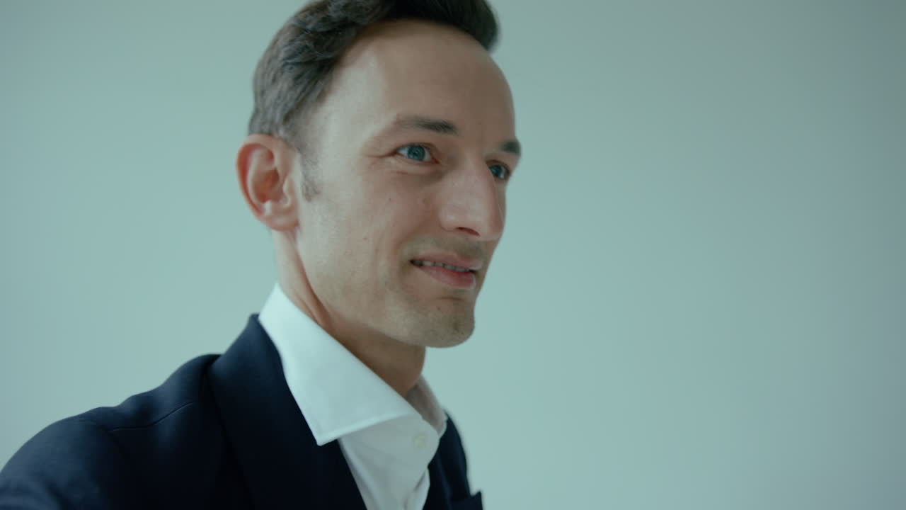 Uomo elegante e affascinante in completo che si abbottona la giacca e sorride, ripresa in tilt-up.
