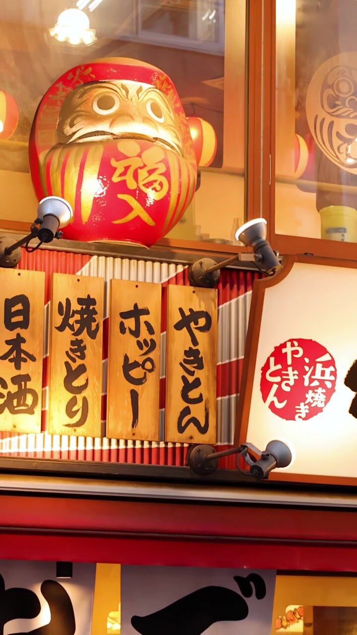 Primo piano della facciata di un tradizionale izakaya di Tokyo con menu, tende noren e un Daruma