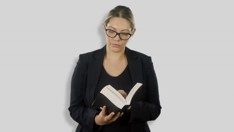 una atractiva mujer de negocios de cabello rubio con anteojos está leyendo la biblia