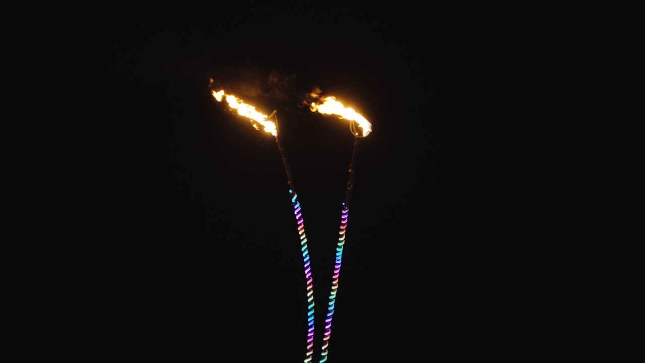 dos antenas con puntas de llama roja iluminan la noche mientras los tubos de luz de neón multicolores del arco iris iluminan sus marcos delgados