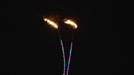 Dos-Antenas-Con-Puntas-De-Llamas-Rojas-Iluminan-La-Noche-Mientras-Tubos-De-Luz-De-Neón-Multicolores-Iluminan-Sus-Delgados-Marcos.