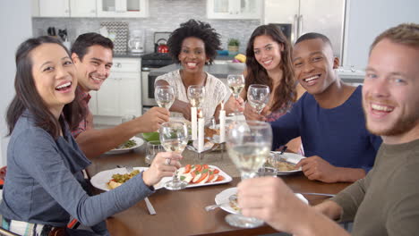 Friends-at-dinner-table-make-a-toast-to-camera,-slow-motion