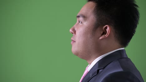 joven apuesto hombre de negocios asiático con sobrepeso contra un fondo verde