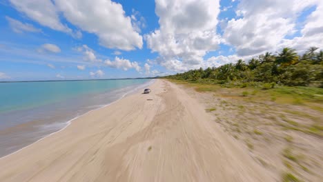 vuelo dinámico fpv en la playa de miches town, siguiendo un mini cooper gris en la orilla de la playa