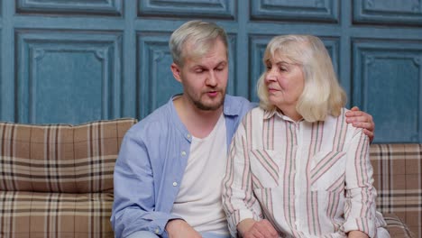 Family-of-senior-mother-embracing-adult-son-or-grandson-and-having-heart-to-heart-conversation