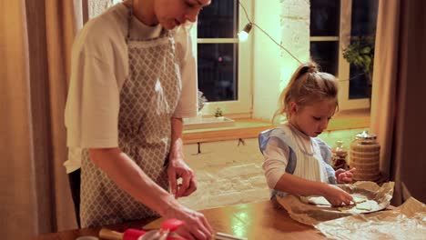 mother and daughter baking cookies together at night