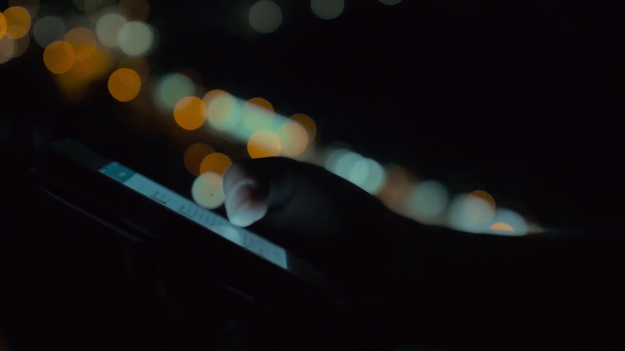 밤의 도시 불빛의 배경에서 스마트 폰을 사용하는 것