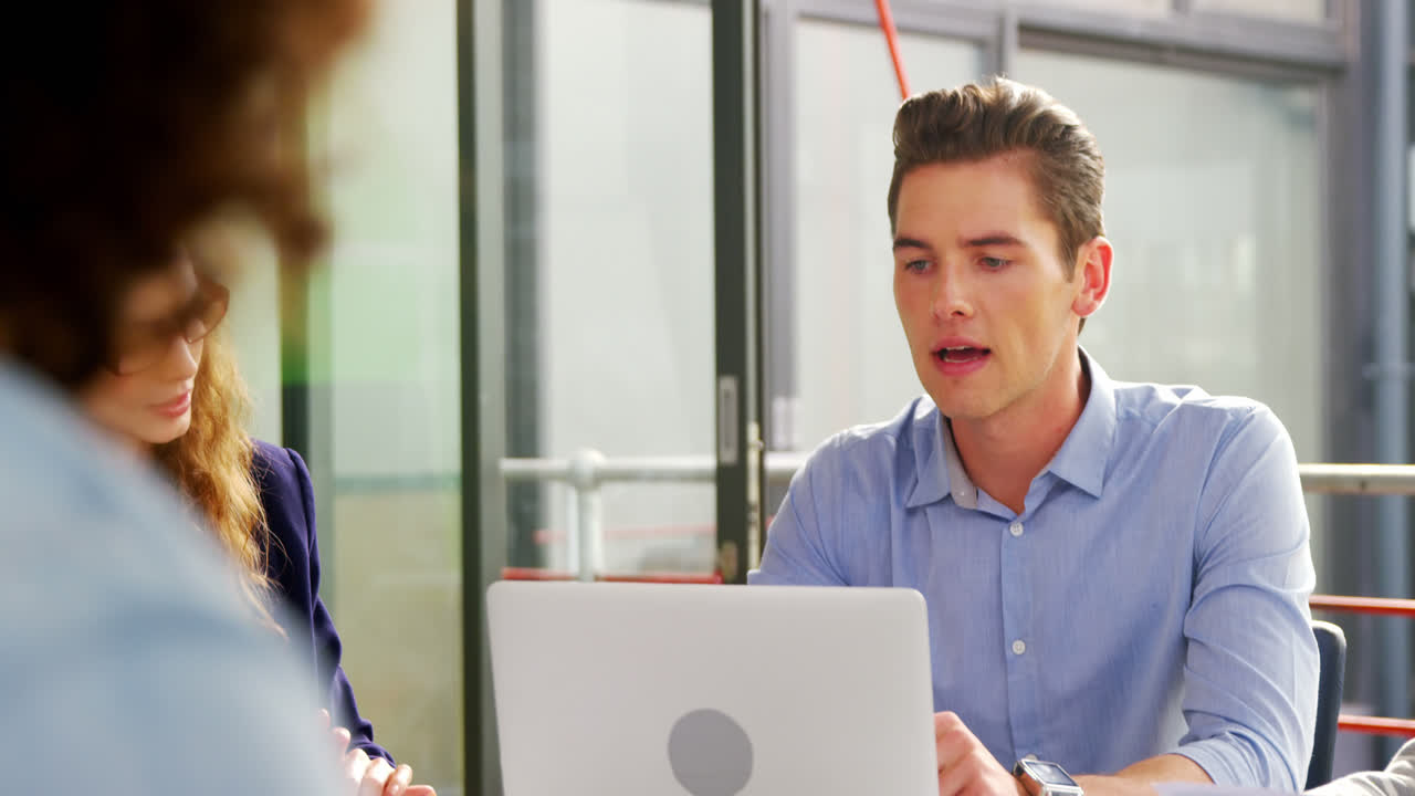 비즈니스 임원 들 이 회의 에서 노트북 을 통해 논의 하고 있다