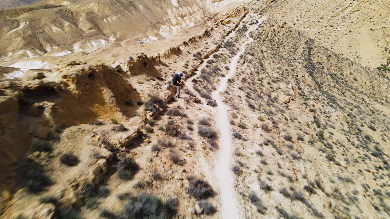 푸른 하늘과 함께 화창한 날에 멋진 풍경을 보여주는 사막 트레일에서 산등성이와 하이커 위로 낮게 날아가는 공중