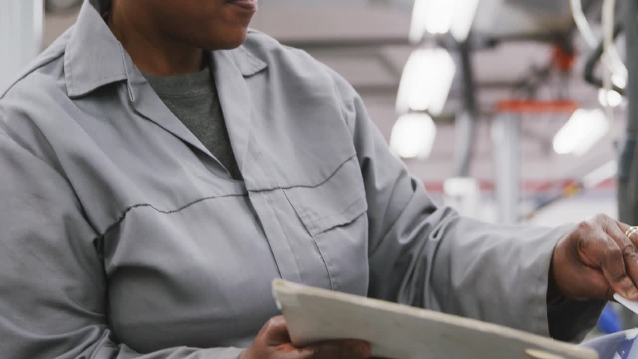 African American female car mechanic painting a body of a car