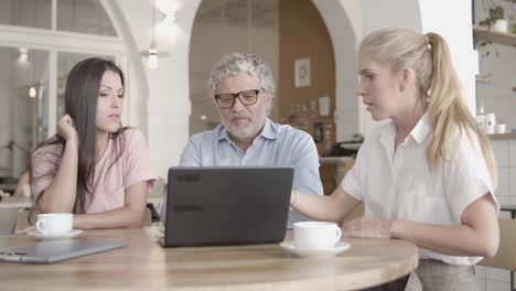 successful businesswomen showing data via laptop and explaining to mature man