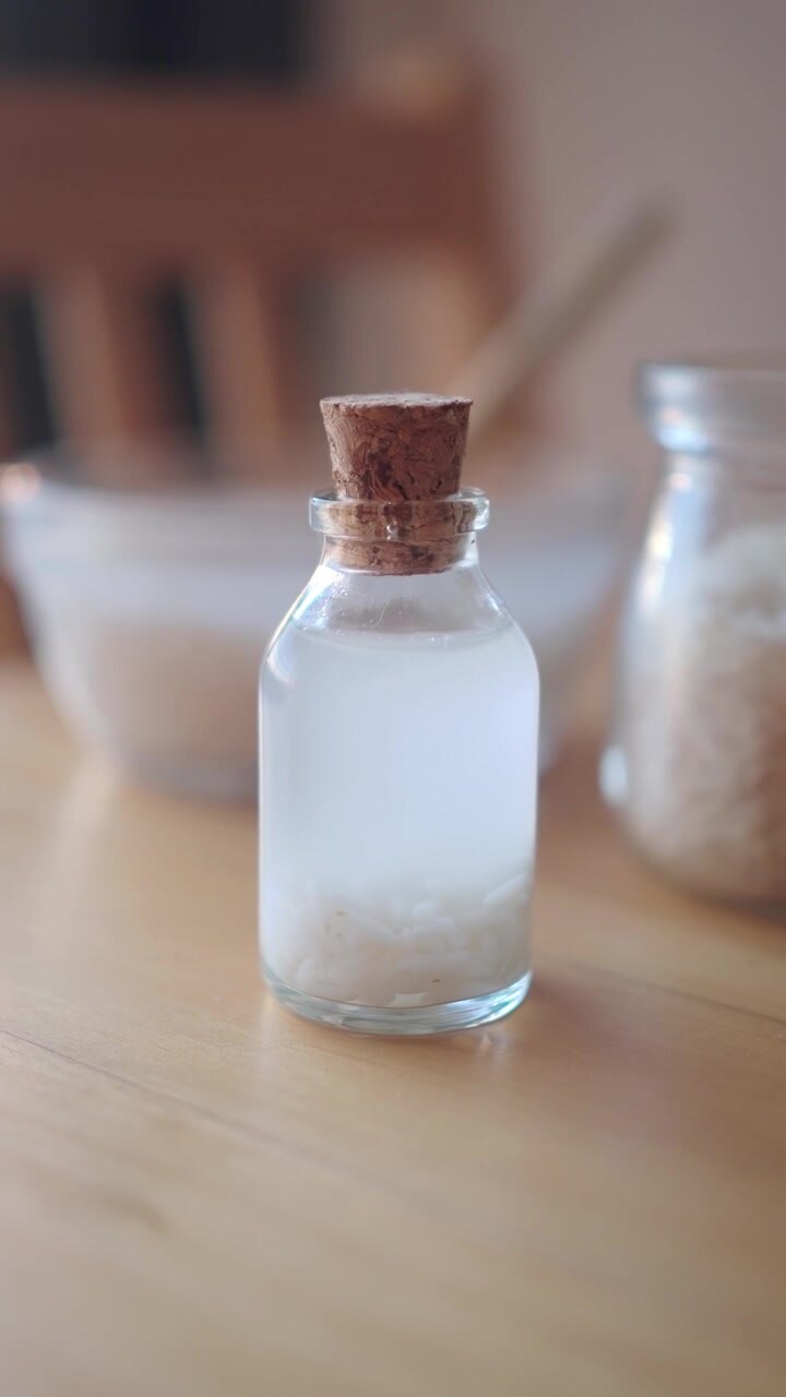 Small Glass Bottle Containing Rice Water on Wooden Table