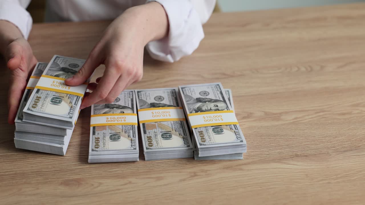 A person's hands stacking bundles of US dollar bills