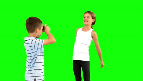 Brother-taking-pictures-of-his-sister-jumping-on-green-screen