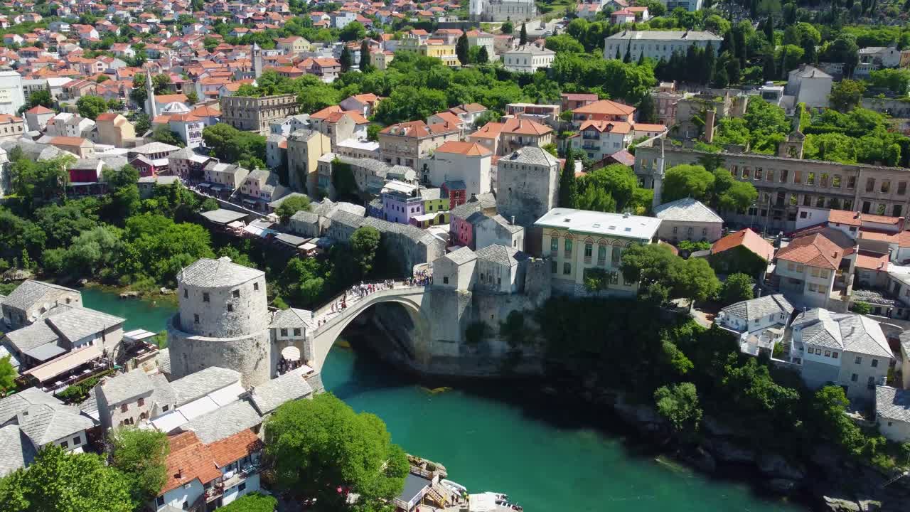Aerial drone footage of Mostar, Bosnia and Herzegovina, showcasing the iconic Old Bridge (Stari Most), winding turquoise Neretva River, and historic Ottoman-style architecture