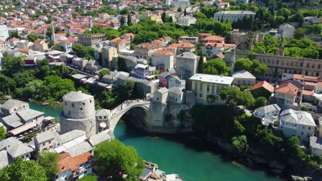 aerial drone footage of mostar, bosnia and herzegovina, showcasing the iconic old bridge (stari most), winding turquoise neretva river, and historic ottoman-style architecture