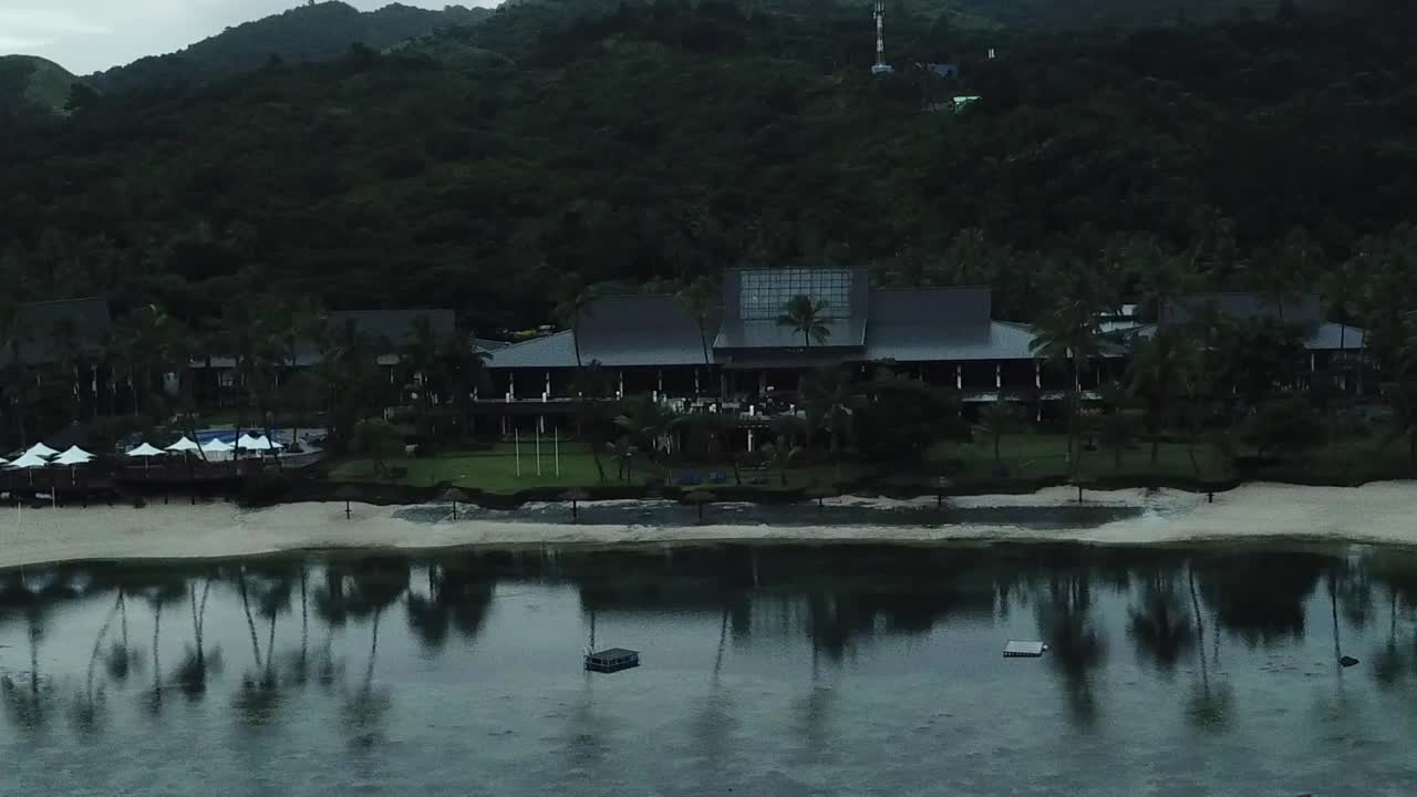 imágenes de drones sobre el hotel de playa de la costa de coral the warwick al amanecer con palmeras que se reflejan en el océano en calma
