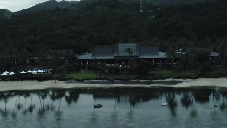 Drone-footage-over-Coral-Coast-beach-hotel-The-Warwick-at-sunrise-with-palm-trees-reflecting-in-calm-ocean