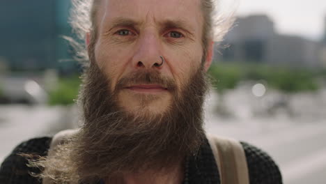 close-up-porträt eines ernsthaften, reifen hippie-mannes, der nachdenklich auf die kamera schaut, intensiver im städtischen hintergrund.