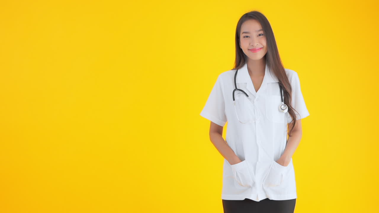 A woman dressed in a white smock and stethoscope has her hands in her pockets copy space to her right