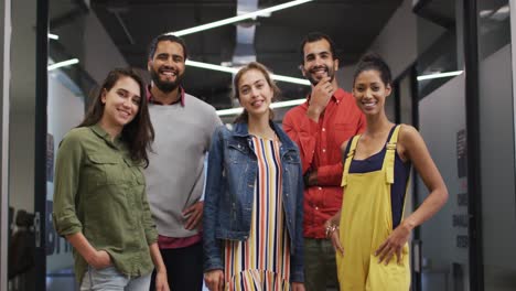 portrait of diverse group of work colleagues standing in corridor smiling to camera