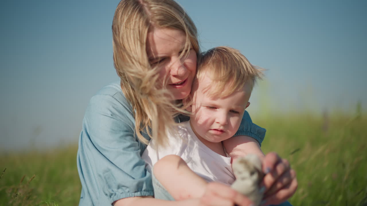 madre ayudando a su hijo a ponerse los calcetines en un campo de hierba soleada con amor cuidadosamente