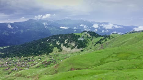 aerial view from drone of green mountain plateau with small village on the slope