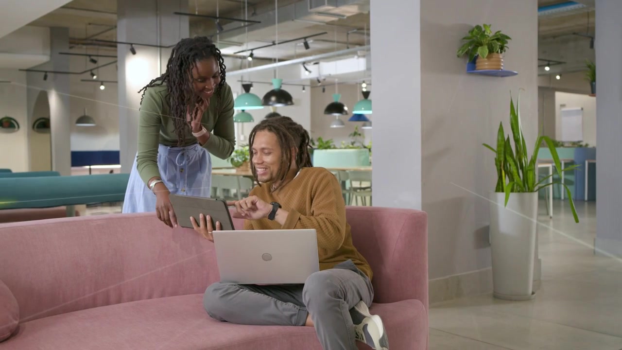 Woman showing tablet, man leaning in, exchanging devices and reviewing tech data overlays