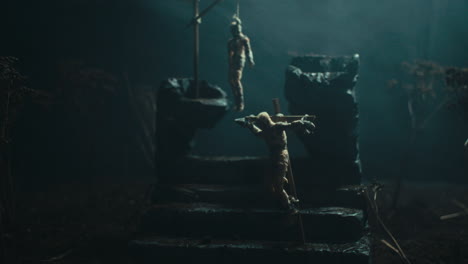 a miniature scene of the mummified dolls hanging on the gallows at night
