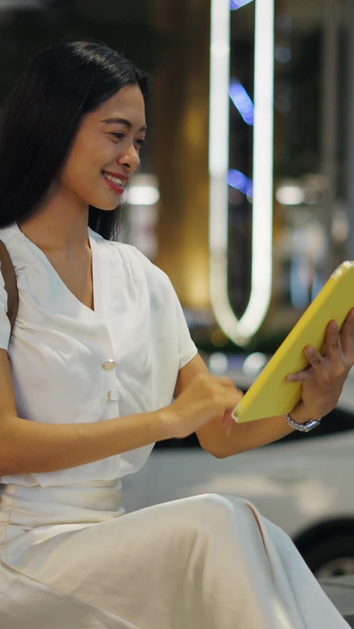 Woman using tablet on the street at night