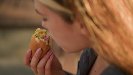 toma de primer plano de alguien tomando un bocado de shawarma, centrándose en la mano y el momento de comer, con un fondo borroso