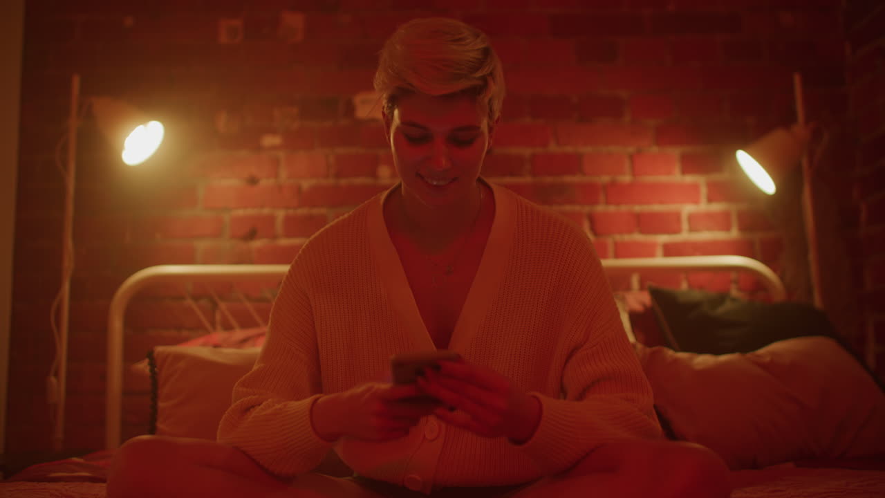 Woman using phone in a red lit bedroom
