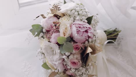 beautiful wedding bouquet lie with wedding rings near window on white curtains