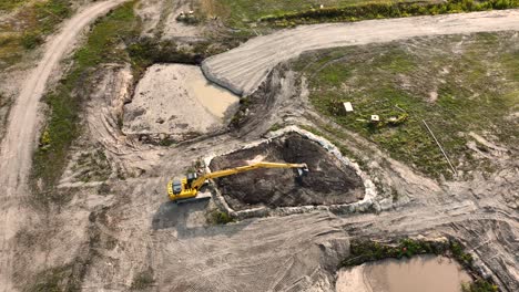 a heavy machine digger filling in a man made pond on a construction site