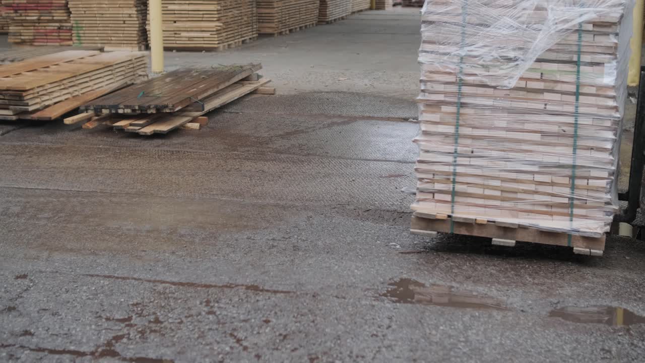 Gaffeltruck flytter stablede træplanker på en palle på et trælastlager