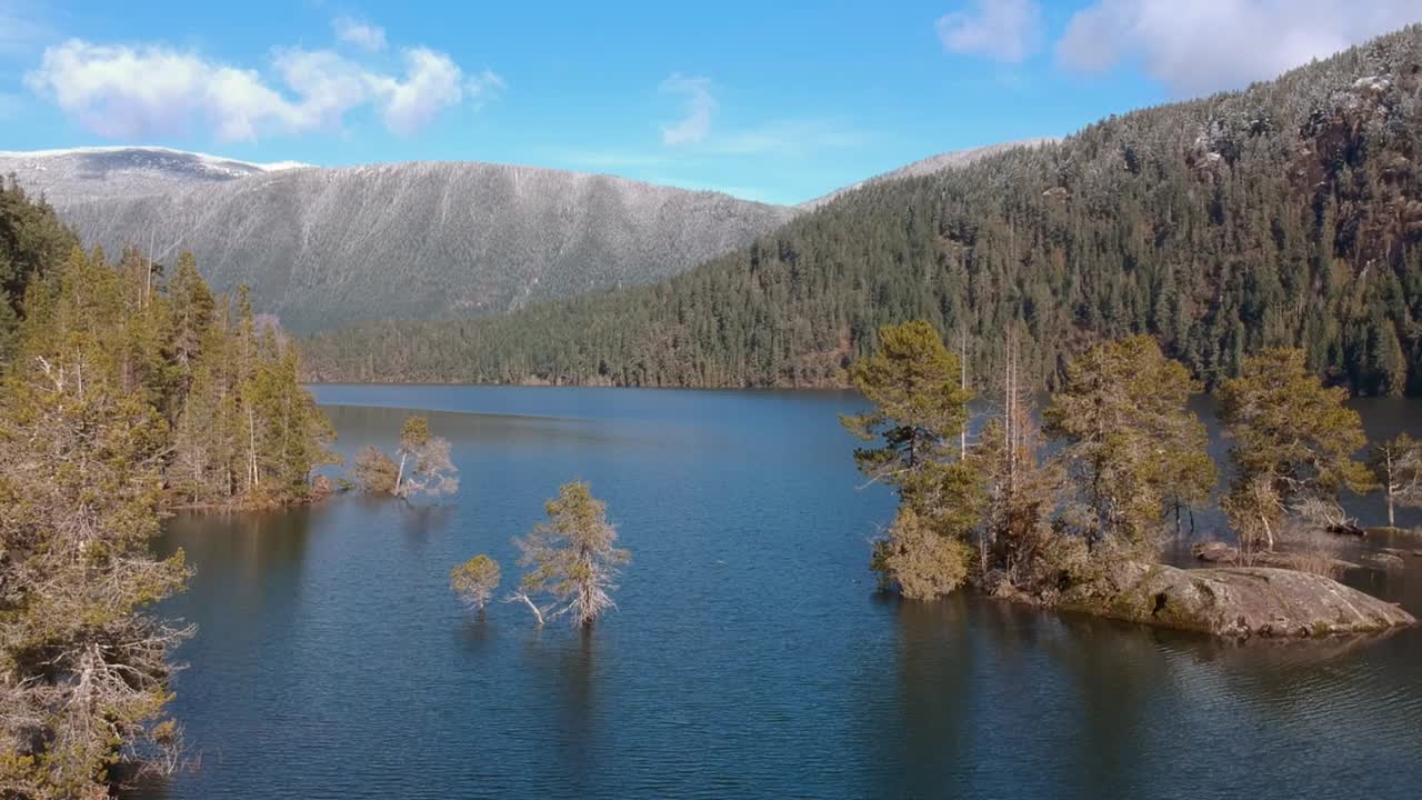 Drone pull back shot of Cowichan Lake on Vancouver Island British Columbia Canada overlooking frosty mountain , lake , forest and sub merged small island.