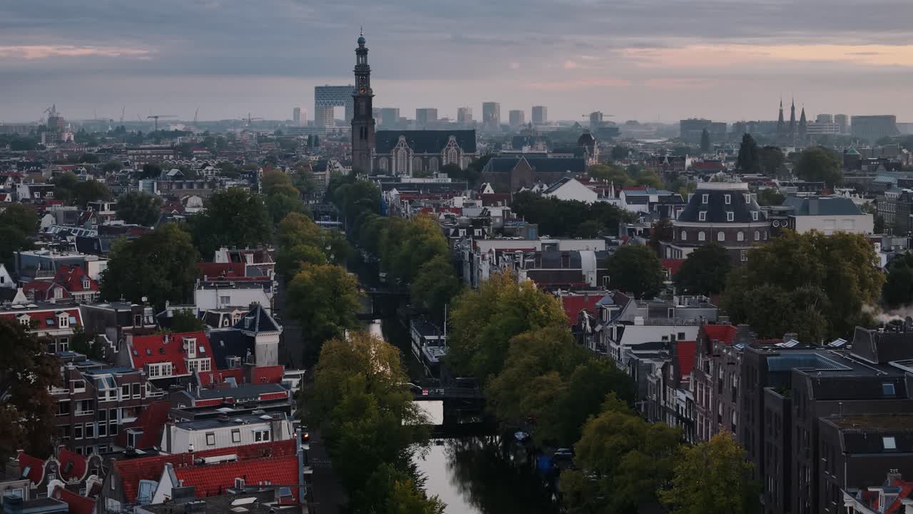 Drone ascend rising towards church and canal during sunrise in Amsterdam, panoramic establishing overview