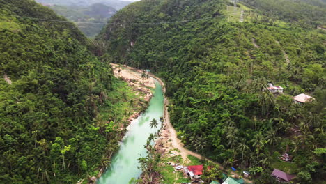 revelando la caída de una pequeña aldea a lo largo de un río en un bosque en cebu filipinas, aéreo, avión no tripulado, cinematográfico, asia