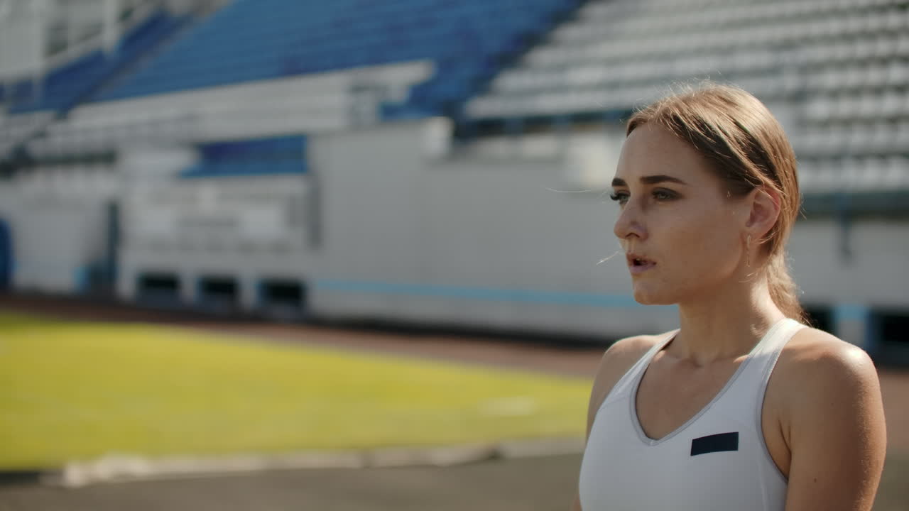 느린 움직임: 여자 운동 선수가 400 미터에서 경주 시작을 기다립니다. 여자 운동 선수는 100 미터 동안 경주를 시작하기를 기다립니다. 트레드밀의 패드에서 경기장에서 달립니다.