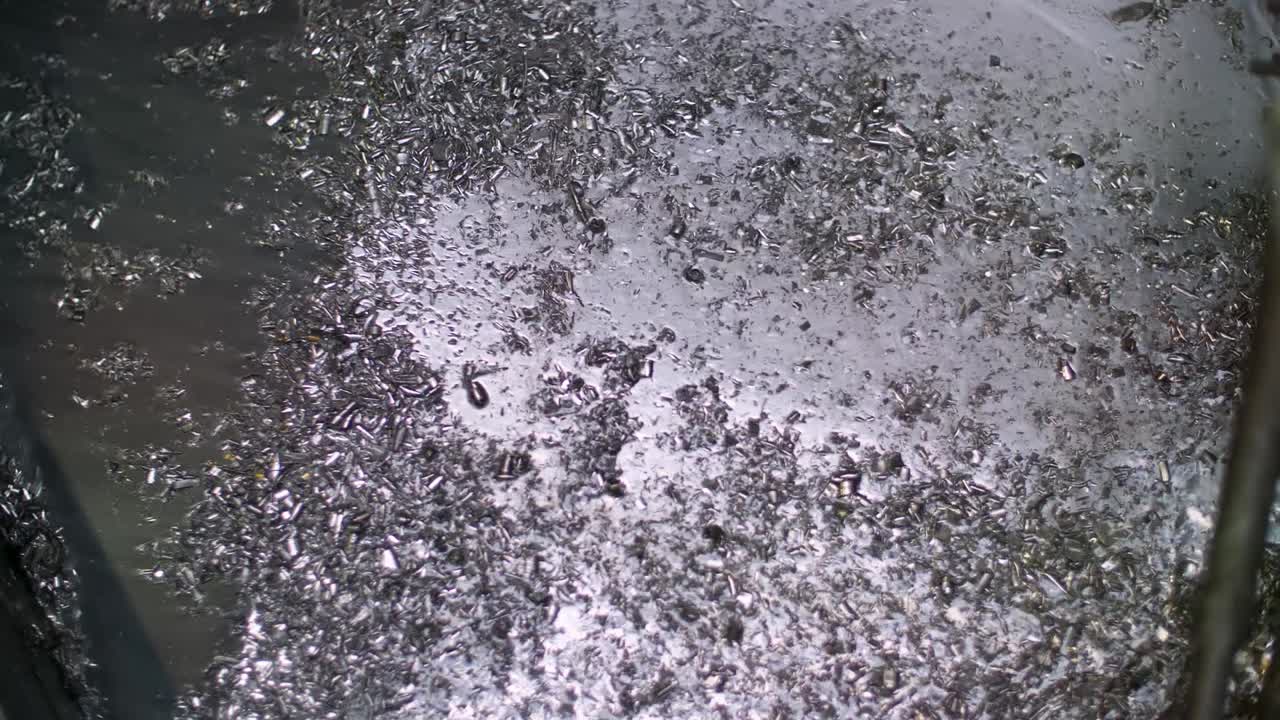 작은 금속 조각이 재활용 공장의 경사로 아래로 진동합니다.